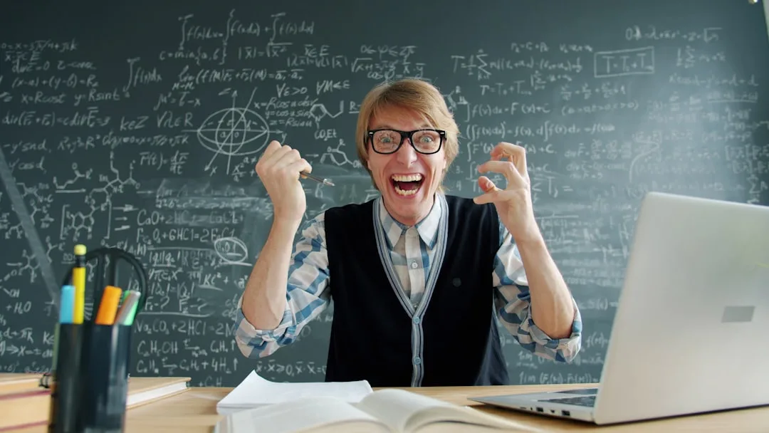 Excited man in glasses celebrating in front of blackboard.