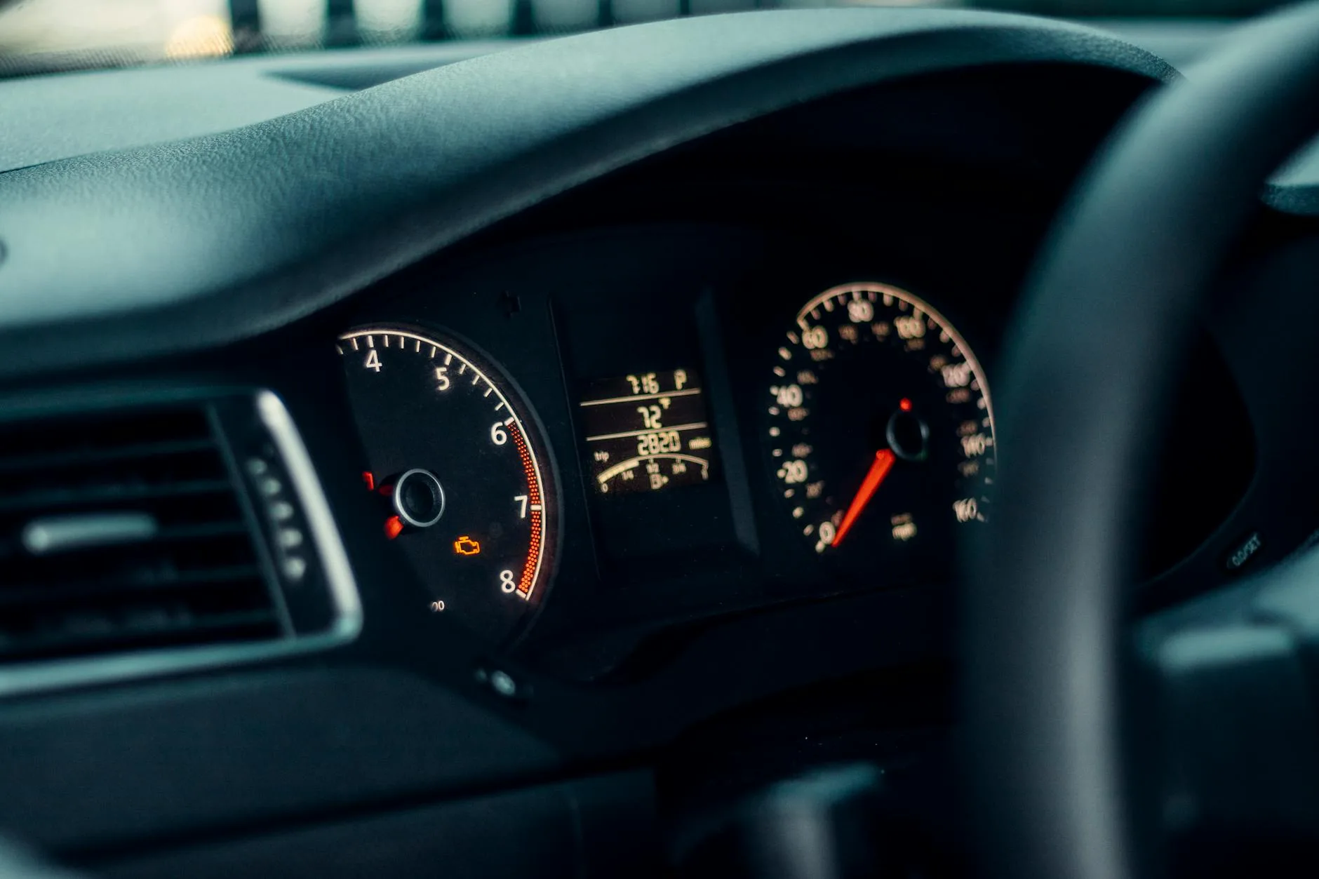 Detailed view of a car's dashboard featuring illuminated gauges and speedometer.