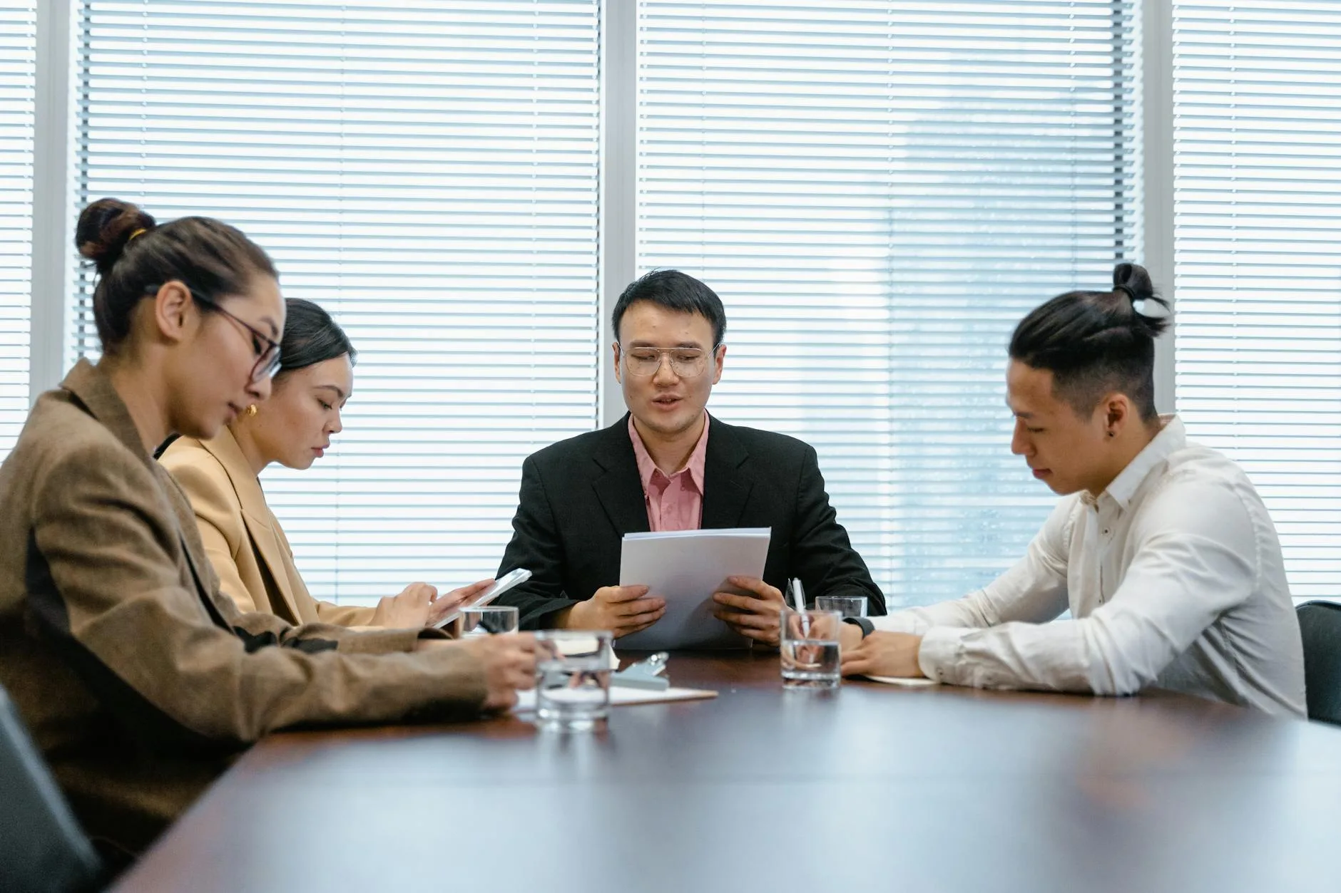 Professional business team engaged in a meeting around a conference table in a modern office setting.