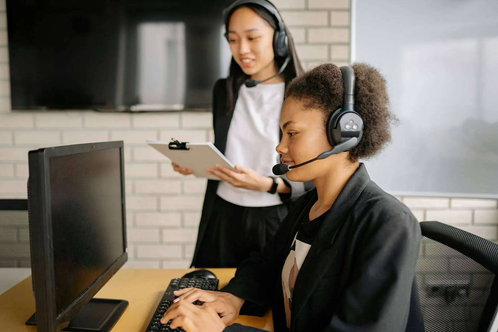 Two professional women working in a call center, focused on customer support in a modern office environment.