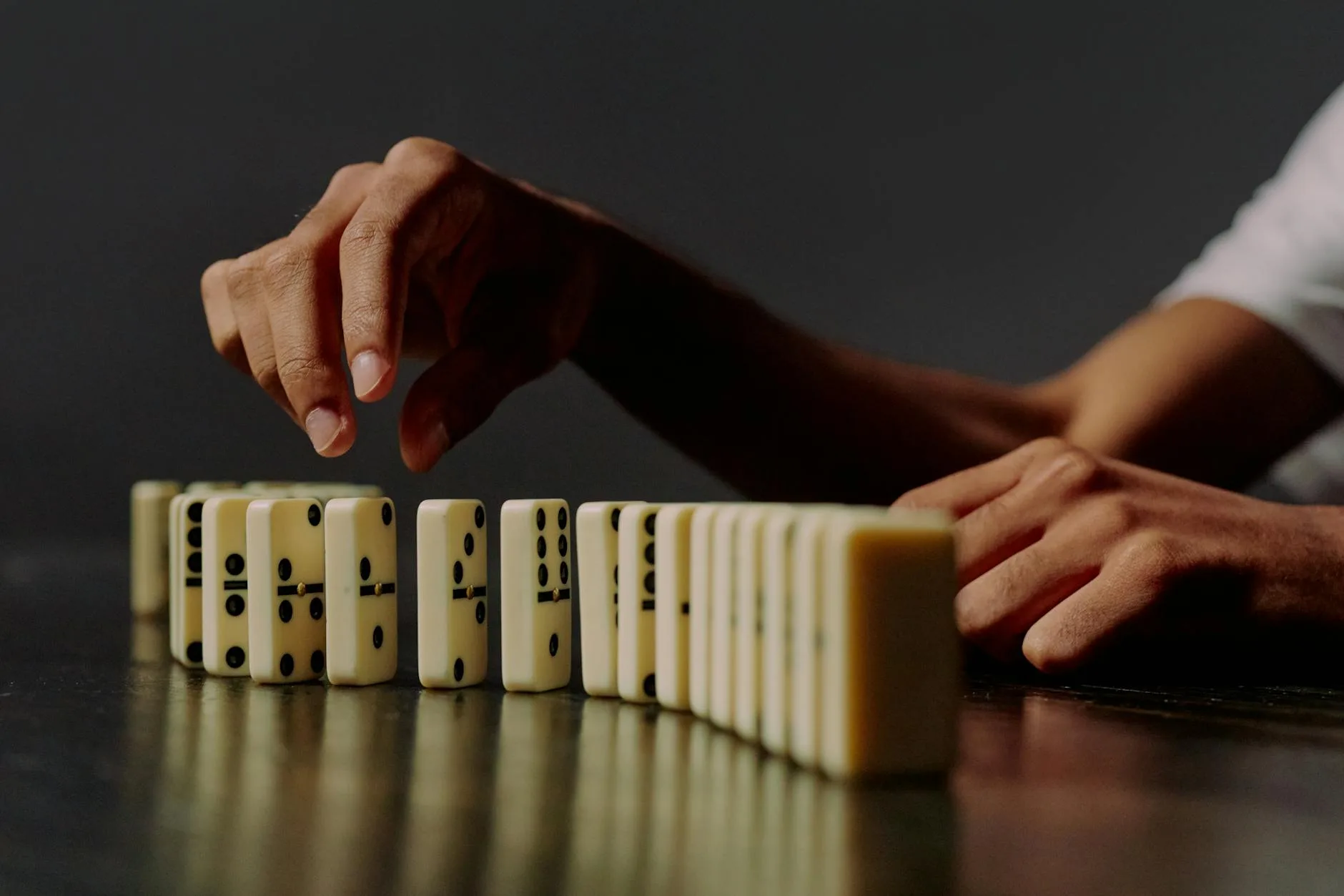 A detailed shot of hands placing dominoes in a row, symbolizing strategy and precision.