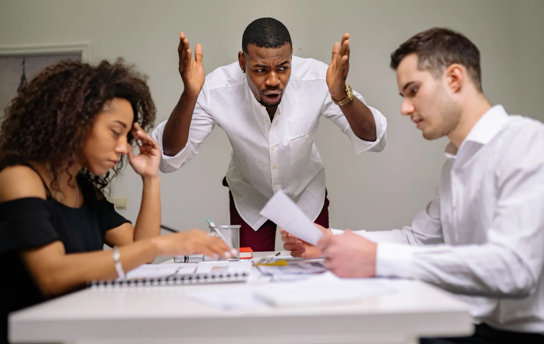 Three colleagues in a heated argument at the office, highlighting workplace stress.