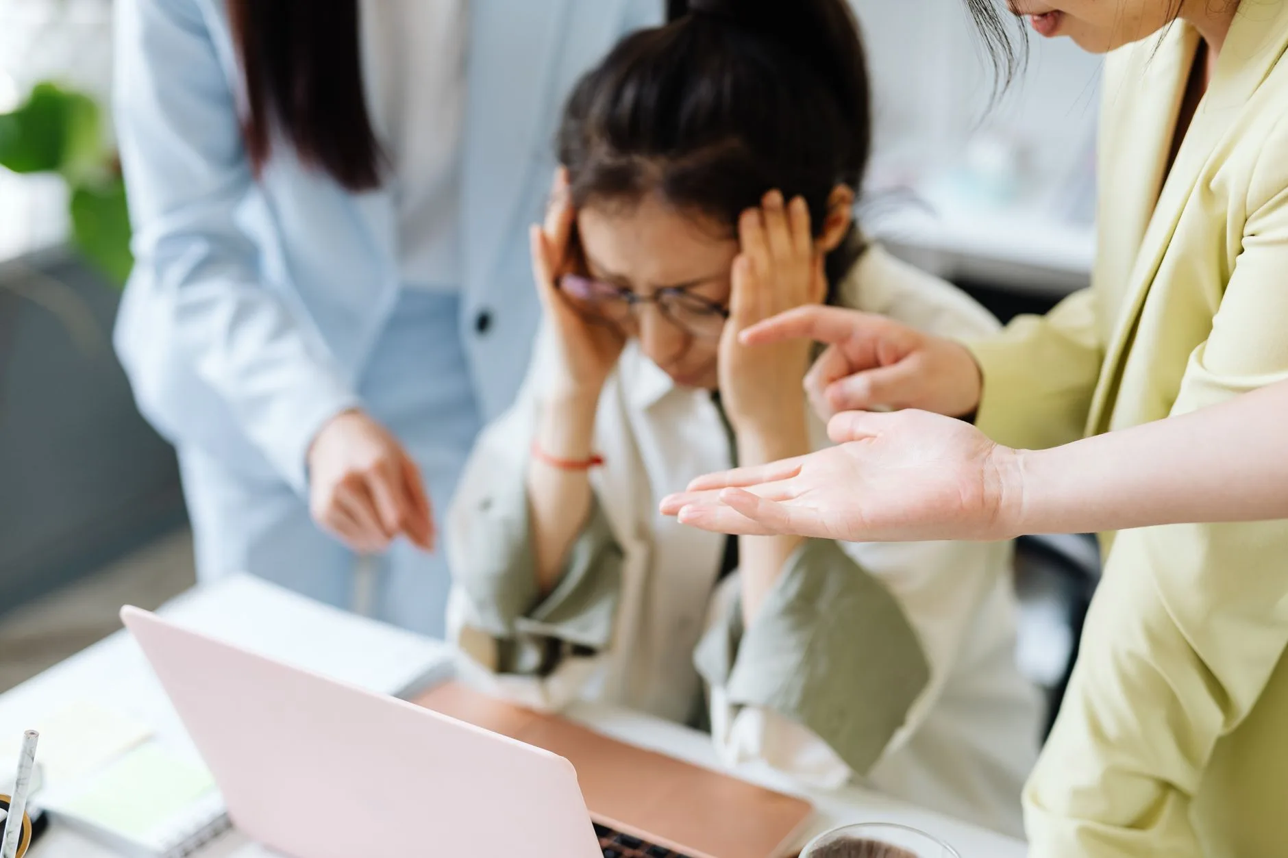 A stressed woman with colleagues in an office, showcasing teamwork and workplace dynamics.