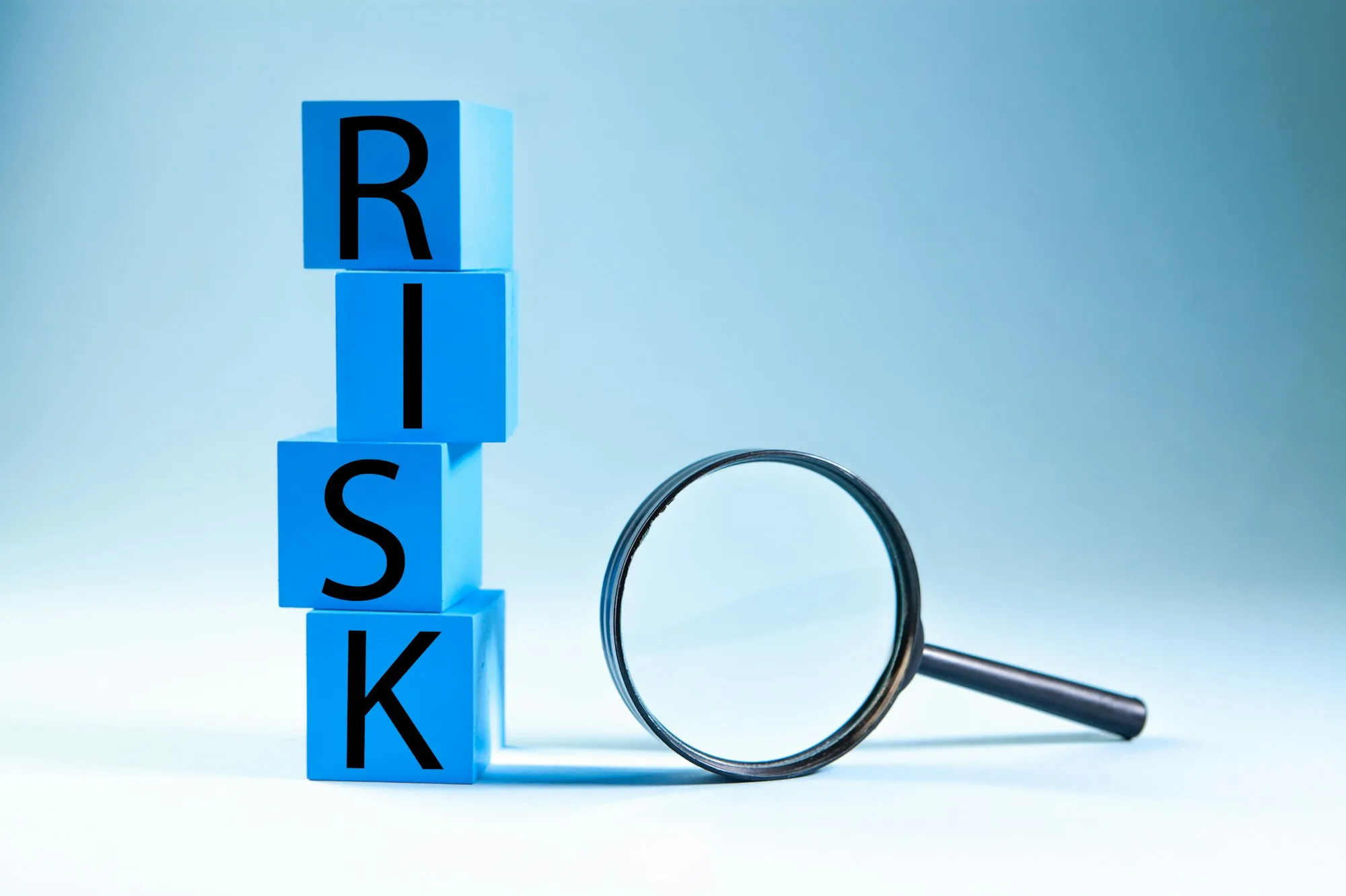 Khối chữ RISK cạnh kính lúp, minh họa cảnh báo rủi ro bằng AI trong quản lý dự án